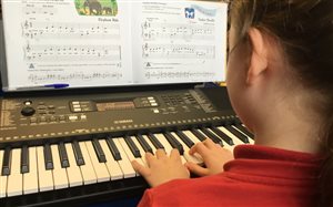 A student concentrating whilst learning Piano in School